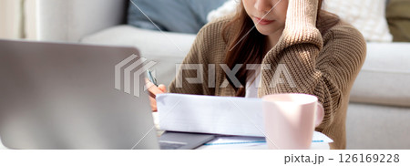 Young asian woman checking document about finance with stress and worried in living room. 126169228