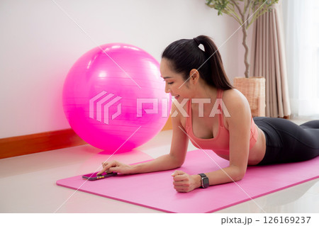 Young asian woman practice workout with posing plank on mat while motivation and determined. 126169237