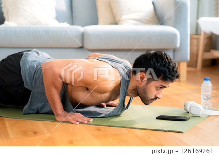 Young asian man doing pushup exercise in living room at home with determination. 126169261