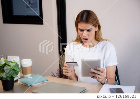 Young caucasian woman holding credit card or debit card paying with shopping online. Young caucasian woman holding credit card or debit card paying with shopping online. 126169323