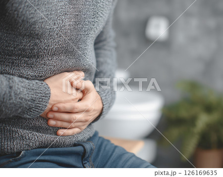 トイレで手でお腹を押さえる男性。腹痛や胃痛、ストレスを表す体調不良のイメージ 126169635