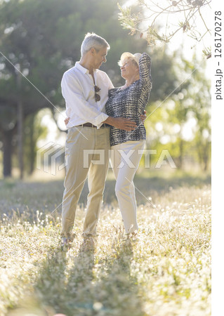 Senior couple embracing in a sunny meadow during retirement days 126170278