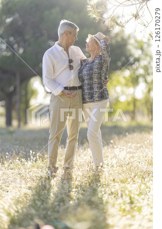 Happy senior couple embracing in a sunny meadow at sunset 126170279