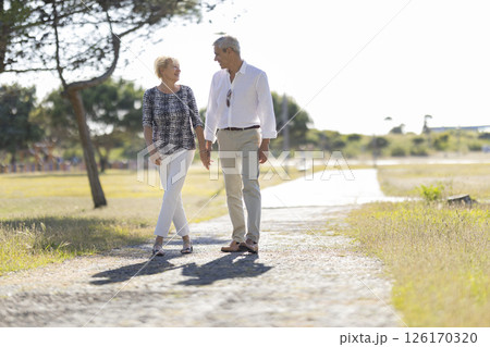 Happy senior couple walking on a path in a park Happy senior couple walking on a path in a park 126170320