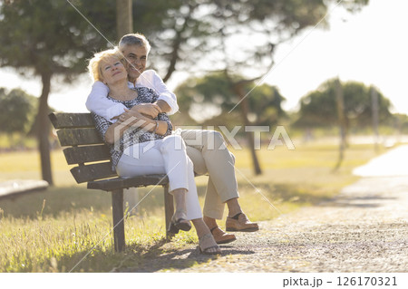 Happy senior couple embracing on park bench during retirement Happy senior couple embracing on park bench during retirement 126170321