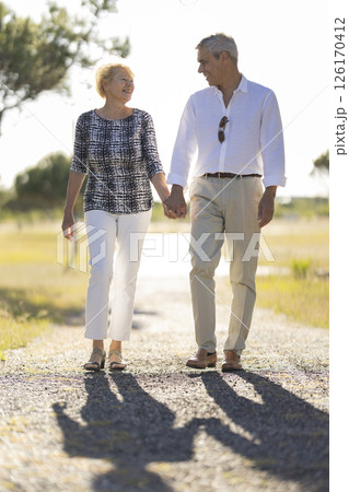 Happy senior couple walking on a country road holding hands 126170412