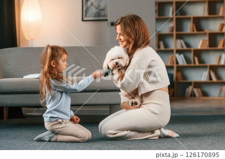 Woman is giving pet for the girl. Present for the daughter. Mother is at home with maltese dog 126170895