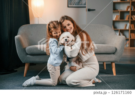 On the floor with pet together. Mother with daughter is at home with maltese dog 126171160