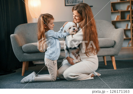 On the floor with pet together. Mother with daughter is at home with maltese dog 126171163