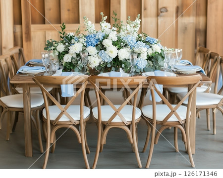 Indoor banquet with white and blue flowers, plates, crystal glasses, elegant and intimate setting. 126171346