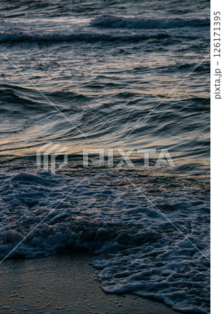 Ocean with waves, sunset sky is orange. water is choppy and waves are crashing on shore. 126171395