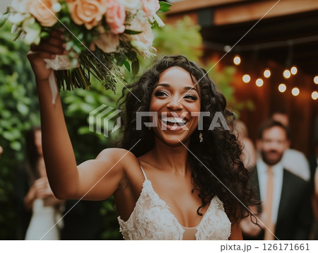 The bride is tossing the bouquet, standing with her back to the bridesmaids. It's a joyful wedding tradition. 126171661