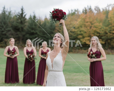 The bride is tossing the bouquet, standing with her back to the bridesmaids. It's a joyful wedding tradition. 126171662