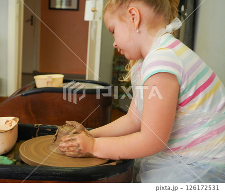 Child hands make earthenware cup working on pottery wheel at workshop. Child hands make earthenware cup working on pottery wheel at workshop. 126172531