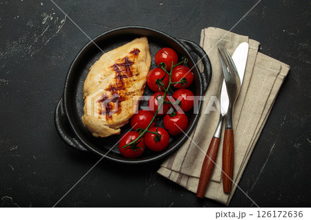 Grilled chicken breast fillet with cherry tomatoes in cast iron pan top view on rustic black background, healthy food Grilled chicken breast fillet with cherry tomatoes in cast iron pan top view on rustic black background, healthy food 126172636