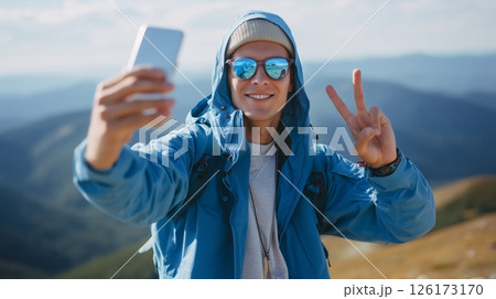 Young hiker takes a selfie while enjoying a beautiful mountain landscape on a sunny day in nature 126173170