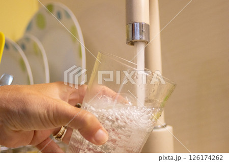 Close-up of water pouring from a kitchen tap, symbolizing sustainable living Close-up of water pouring from a kitchen tap, symbolizing sustainable living 126174262