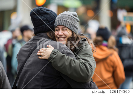 Two people joyfully embrace in a crowded street, radiating happiness and love. Their connection is evident, offering support and comfort 126174560