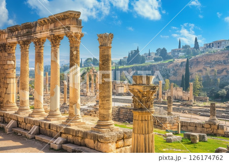 Majestic ruins of an ancient roman city bathed in the golden light of a sunny day, with a modern cityscape in the background 126174762