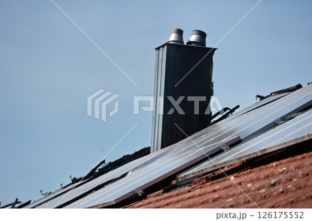 A black chimney on a roof with a blue sky in the background A black chimney on a roof with a blue sky in the background 126175552