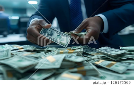 Closeup of a businessperson carefully counting hundred-dollar bills on a table 126175569