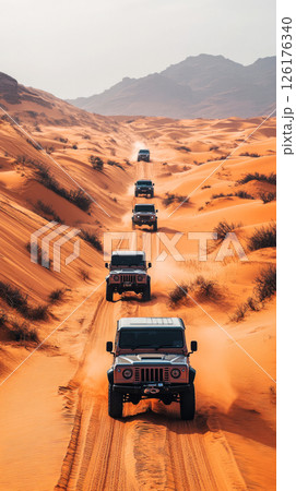 Convoy drives through deep dunes, sun blazing and sand swirling as off-road rigs push across wild heat in a raw test of power and grit 126176340