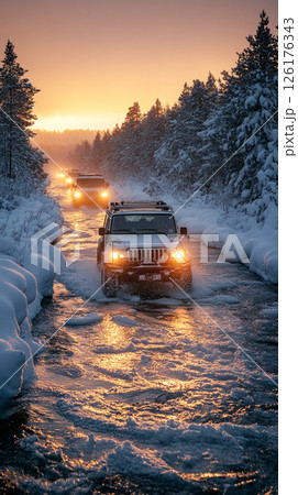 Bold winter scene with three trucks forging through icy riverbanks under thick snow, their tires gripping frost and steel strength pushing through harsh wilderness 126176343
