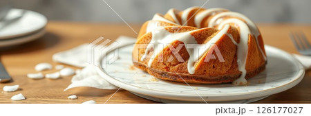Delicious bundt cake served on a rustic wooden table with white icing drizzled on top during a cozy afternoon 126177027