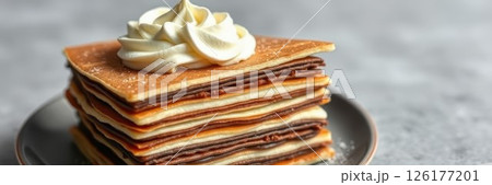 Delicious layered dessert with cream topping served on a plate, perfect for dessert lovers at any gathering 126177201