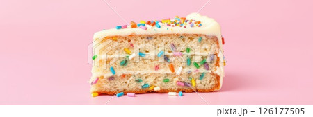 Colorful cake slice with frosting and sprinkles on a pink background showcasing dessert art 126177505