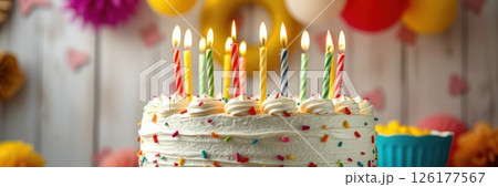 Celebrating a joyful birthday with a colorful cake and lit candles at a festive gathering 126177567