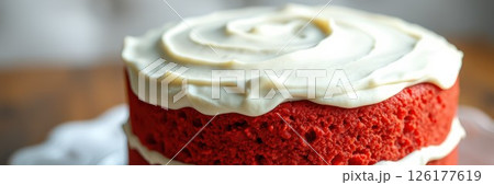 Delicious red velvet cake with cream cheese frosting displayed on a rustic wooden table 126177619