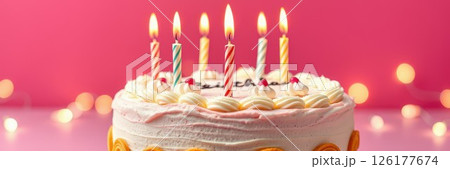 Celebratory birthday cake with colorful candles glowing against a vibrant pink background 126177674
