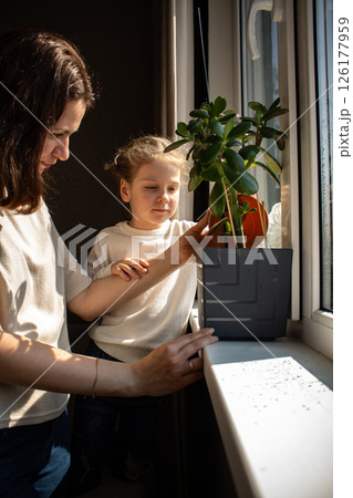 4 years old girl and her mom engage in plant care. Illustrating gentle parenting and eco habits. Image for educational materials, parenting guides, and home gardening content. 126177959