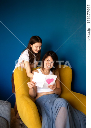 Happy mother's day. Child daughter congratulates moms and gives her gift box and handmade greeting card. 126177965