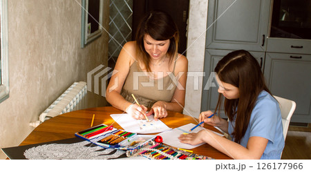 Happy mother and daughter drawing together at home. Family bonding and joyful moments. Childhood memories, love, and art. Perfect for concepts of parenting, education, and quality family time. Happy mother and daughter drawing together at home. Family bonding and joyful moments. Childhood memories, love, and art. Perfect for concepts of parenting, education, and quality family time. 126177966
