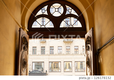 An ancient wooden portal with iron knocker. old wooden door. arch and window with metal decorations. An ancient wooden portal with iron knocker. old wooden door. arch and window with metal decorations. 126178132