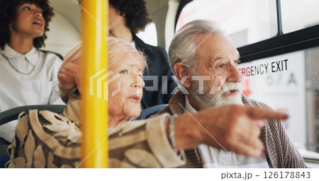 Old couple, travel and talking on bus ride to destination for public transport, holiday or vacation. People, pointing or elderly tourists by window in city for relationship, retirement or adventure 126178843