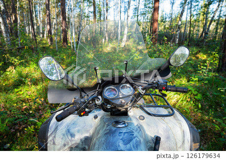 ATV Quad bike parked in a dense forest during a clear day exploring nature's beauty and adventure. All Terrain Vehicle outside 126179634