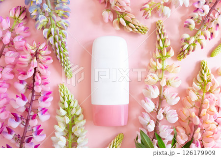 Pink and white cosmetic bottle tube and lupine flowers on pink background, mockup. Daily cream, gel, skin care, sunscreen, moisturizer. Product branding, cream lotion. Front view, blank tube 126179909