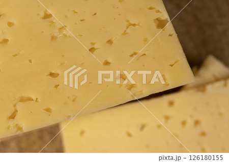 cheese with holes for cooking, pieces of sliced cheese on a board, close up cheese with holes for cooking, pieces of sliced cheese on a board, close up 126180155