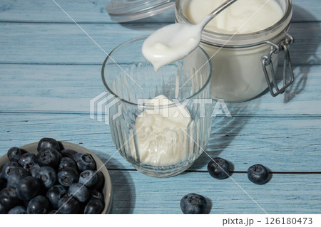 Preparing step by step Morning granola breakfast with homemade greek yogurt, blueberries in glasses on blue wooden background. Healthy diet Crunchy granola with yogurt nuts and blueberries 126180473