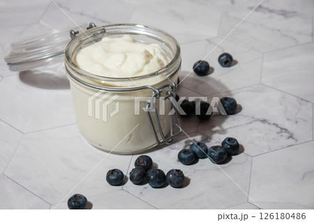 Glass jar with natural organic homemade yogurt and blueberries on table. Immunity-boosting ingredients. Concept of healthy eating breakfast of Greek yogurt. Fermenting superfood 126180486