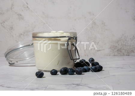 Glass jar with natural organic homemade yogurt and blueberries on table. Immunity-boosting ingredients. Concept of healthy eating breakfast of Greek yogurt. Fermenting superfood Glass jar with natural organic homemade yogurt and blueberries on table. Immunity-boosting ingredients. Concept of healthy eating breakfast of Greek yogurt. Fermenting superfood 126180489