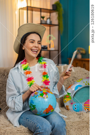 Young woman on sofa with swim ring holding globe and plane tickets planning exciting future trip 126180619
