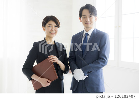 笑顔でファイルを持つビジネススーツ姿の男女 126182407