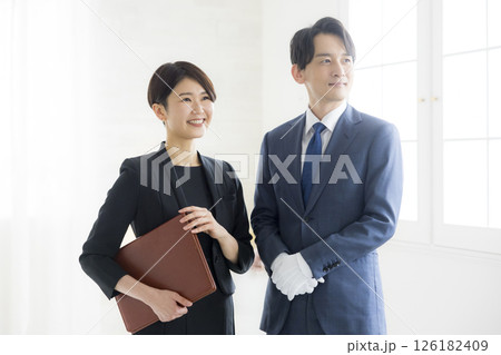 笑顔でファイルを持つビジネススーツ姿の男女 126182409