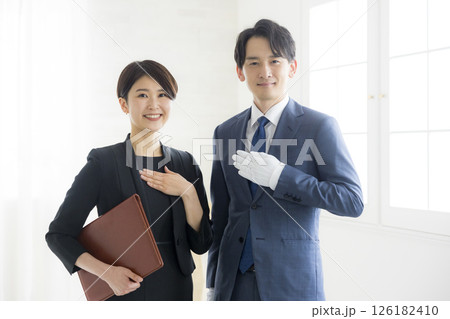 笑顔でファイルを持つビジネススーツ姿の男女 126182410