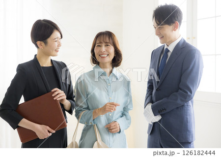 笑顔でファイルを持つビジネススーツ姿の男女  126182444