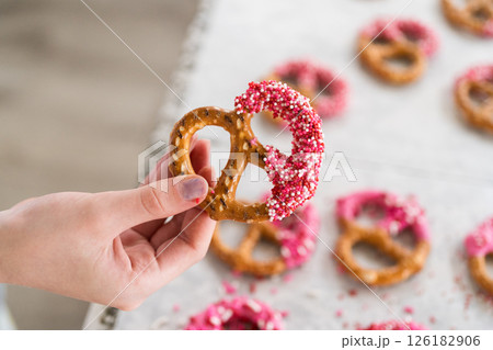 Freshly dipped and still glistening, these crunchy pretzels are lovingly adorned with pink chocolate and a scattering of colorful sprinkles, promising a feast for the senses. Freshly dipped and still glistening, these crunchy pretzels are lovingly adorned with pink chocolate and a scattering of colorful sprinkles, promising a feast for the senses. 126182906